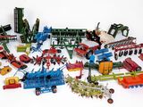 de nombreux tracteurs miniatures et du matériel agricole posés sur une surface blanche