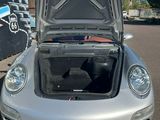 une voiture argentée, le capot ouvert, dans un parking