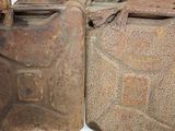 two old rusty jerry cans sitting next to each other