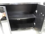 a person opening a metal cabinet with a black door
