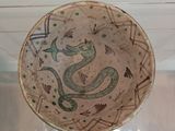 a bowl with a snake on it on display in a glass case