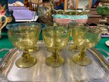 quatre verres posés sur un plateau en argent, sur une table