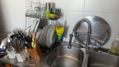 un évier de cuisine avec de nombreux ustensiles posés sur le plan de travail