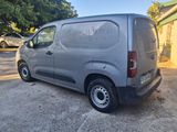 grey van parked in a parking lot with trees in the background