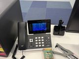 a desk with a phone, keyboard, mouse, and other items on it
