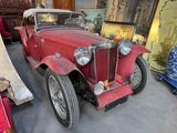 an old red car that is parked in a garage