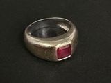 un gros plan d'une bague en argent sertie d'une pierre rouge