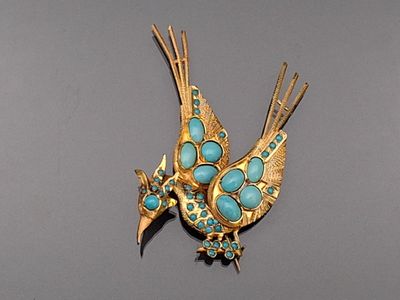 broche en forme d'oiseau plaquée or, ornée de pierres turquoise sur ses ailes