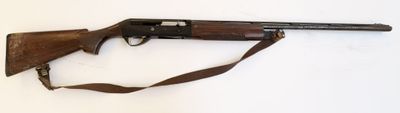le fusil est posé sur une surface blanche, avec une sangle marron