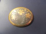 un bouton en or orné de fleurs, posé sur une table