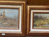 deux tableaux posés sur une table à côté d'un vase de fleurs