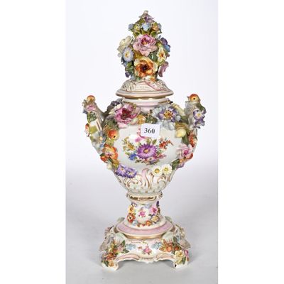 un gros plan d'un vase posé sur un socle et orné de fleurs