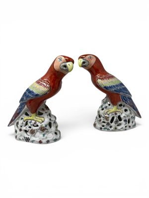 pair of red and green parrots sitting on top of a tree stump