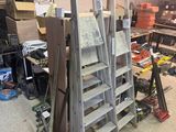 Plusieurs échelles sont empilées les unes sur les autres dans un garage.