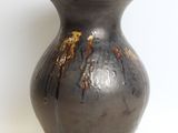 a black vase that is sitting on a white surface