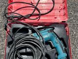 une perceuse filaire dans un coffret rouge posé par terre