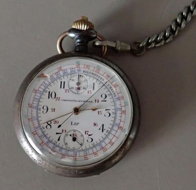 a silver pocket watch on a chain on a table