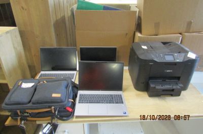 plusieurs ordinateurs portables et une imprimante posés sur une table dans une pièce