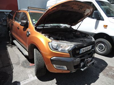 un camion orange dont le capot est ouvert, garé sur un parking
