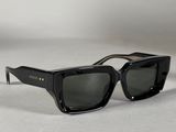une paire de lunettes de soleil noires posée sur une surface blanche