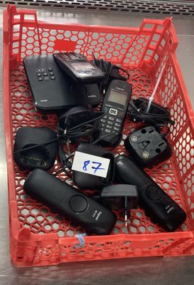 de nombreux téléphones portables dans un panier rouge posé par terre