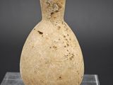 un vieux vase en pierre posé sur un socle en verre