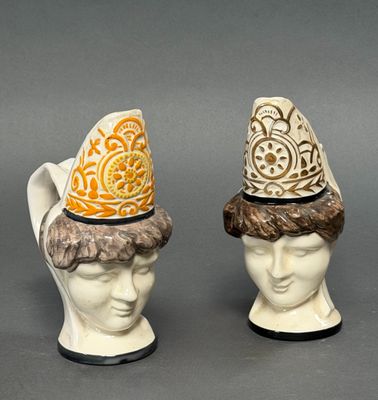pair of ceramic figurines of heads with hats on them