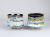 two small cups are sitting side by side on a white surface