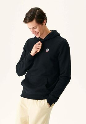Cet homme porte un sweat à capuche noir et un pantalon beige.