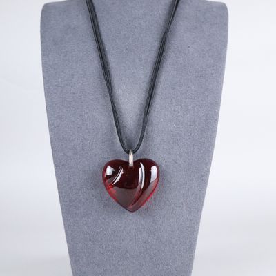 a red heart shaped glass pendant on a black cord necklace