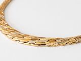 an image of a close up of a gold necklace on a white surface