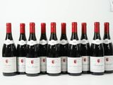 six bouteilles de vin rouge alignées sur une surface blanche