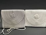 two white purses on a black background with a rope