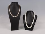 une paire de colliers de perles et un collier posé sur un présentoir pour mannequin