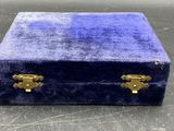 une boîte en velours bleu avec des poignées dorées, posée sur une table