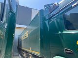 a green truck that is parked next to another truck