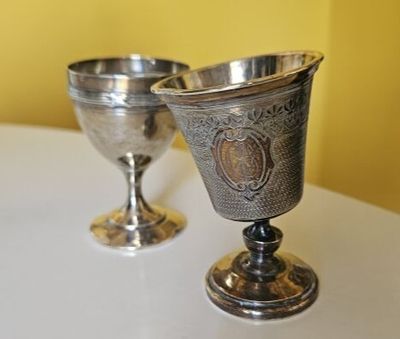 deux gobelets en argent posés l'un à côté de l'autre sur une table