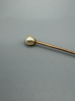 une image représentant une broche en or ornée d'une perle
