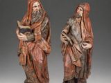 pair of carved wood figures of a man and a woman with a book
