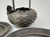 a silver bowl with a handle sitting on a table