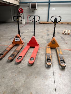 quatre chariots élévateurs qui sont à l'arrêt dans un entrepôt