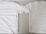 two white t - shirts sitting on top of a table next to each other