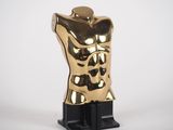 a gold statue of a torso on a black stand