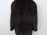 a brown fur coat on a mannequin stand against a white wall