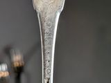 a silver spoon with a design on it sitting on top of a table
