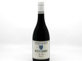 the bottle of wine is sitting on a white surface