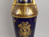 un vase bleu orné de motifs dorés sur fond blanc