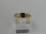 a close up of a gold ring with a red stone on it