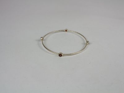 a close up of a silver bracelet with a brown stone