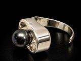 silver ring with a black pearl and diamonds on a black surface